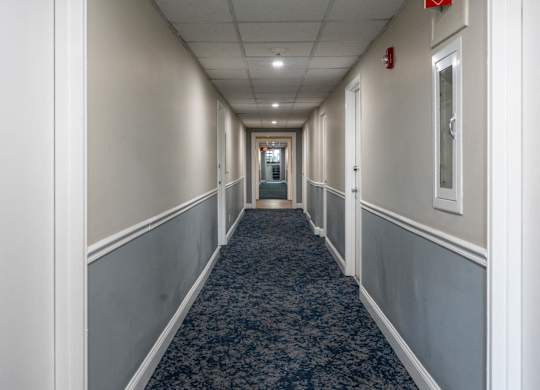 A long hallway with a carpeted floor and white walls.