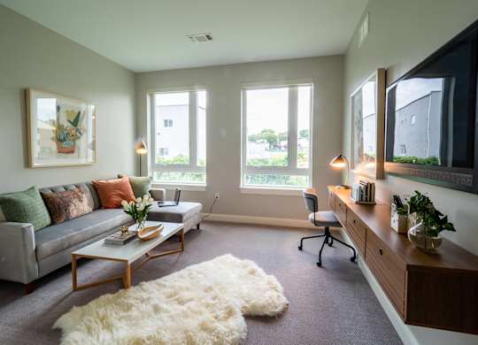 A bedroom setup with a desk area featuring large windows that allow natural light to brighten the room.