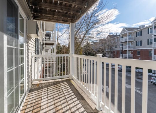 a porch with a white railing and a building in the background