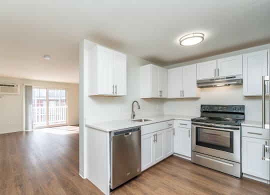 an empty kitchen with white cabinets and stainless steel appliances