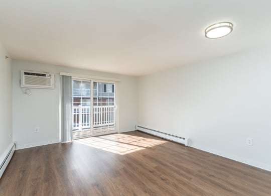 an empty living room with wood flooring and a door to a balcony