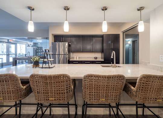 A chic kitchen area with bar seating, pendant lights, and stainless steel appliances.