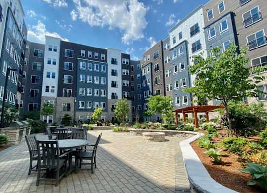 A beautifully landscaped courtyard featuring outdoor dining tables and lush greenery.