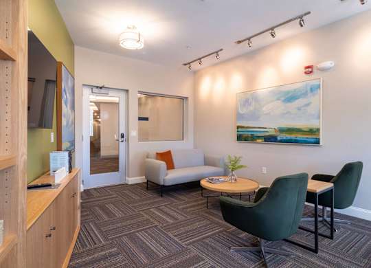 A casual lounge with a modern aesthetic, comfortable chairs, and a TV for relaxation.