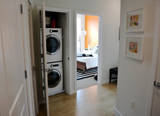 a laundry room with a washer and dryer and a bedroom in the background
