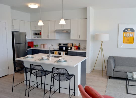 Model apartment kitchen with overhead lights, white counters and breakfast bar