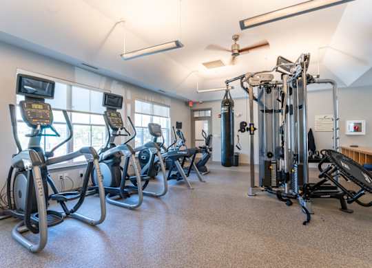 a fitness room with exercise equipment and windows