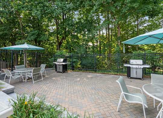 A patio with a table and chairs and a grill.