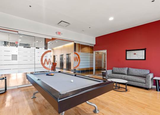 A pool table is in the middle of a room with a couch and a coffee table.