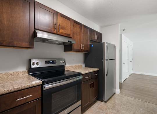 A kitchen with a black stove top oven and a black refrigerator with wooden cabinets.
