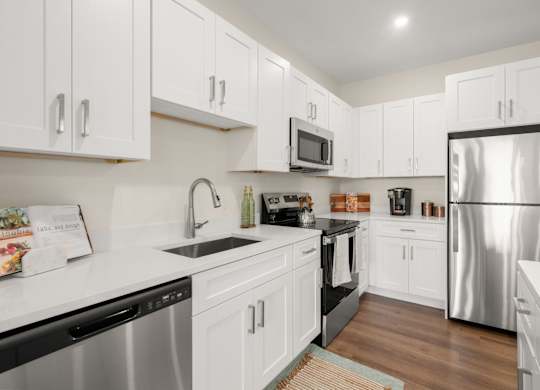 A kitchen with white cabinets and a stainless steel refrigerator.