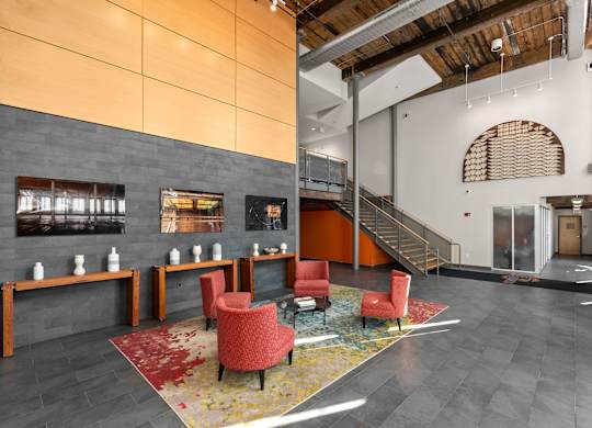 A modern lobby with a staircase and a red chair.