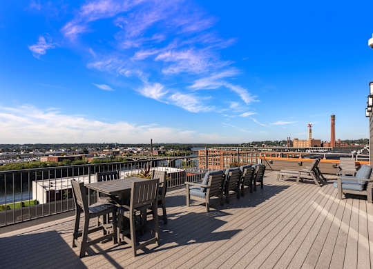 A wooden deck with chairs and a table overlooking a cityscape.