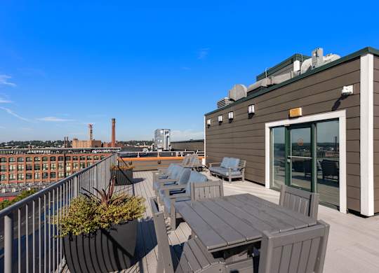 A rooftop patio with a table and chairs overlooking a cityscape.