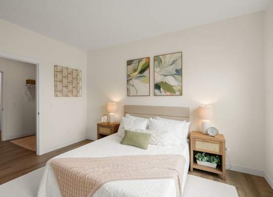 A bedroom with a bed, nightstand, and two wall art pieces.