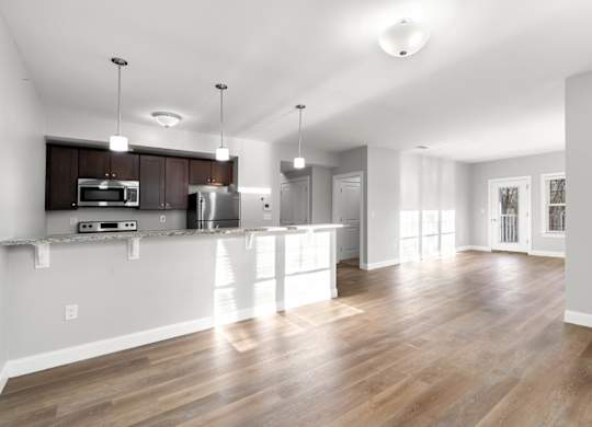 Ashland woods apartments in massachusetts with open floor plans, kitchen in background and living room with large windows.