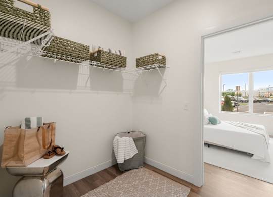A bedroom with a white bed and a window overlooking a cityscape.