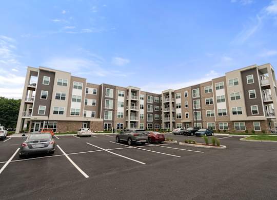 A parking lot in front of a large apartment building.