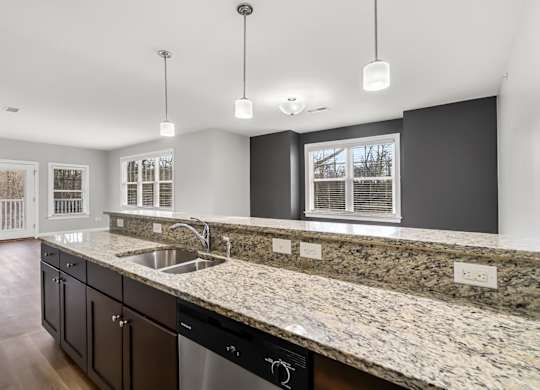 Ashland woods apartment kitchen with stainless steel appliances, stove, microwave, oven, and granite counters. Accent wall in background