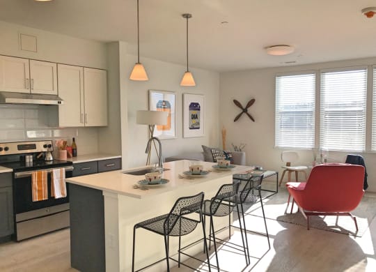 Model apartment kitchen with overhead lights, white counters and breakfast bar