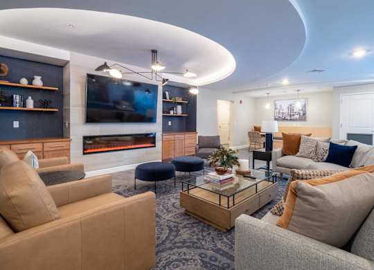 A contemporary social lounge with cozy seating arrangements, a fireplace, and a TV.