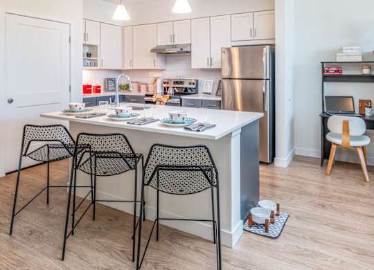 A kitchen with a table and chairs in front of it in model apartment at the Mastlight.