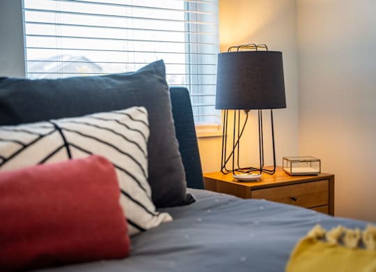A bed with a red pillow and a lamp on a side table at the Mastlight.