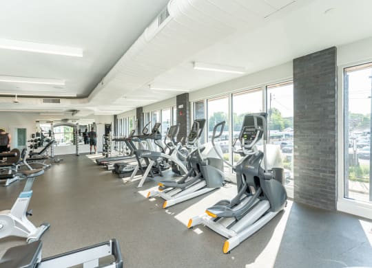 a gym with cardio equipment and windows in a building