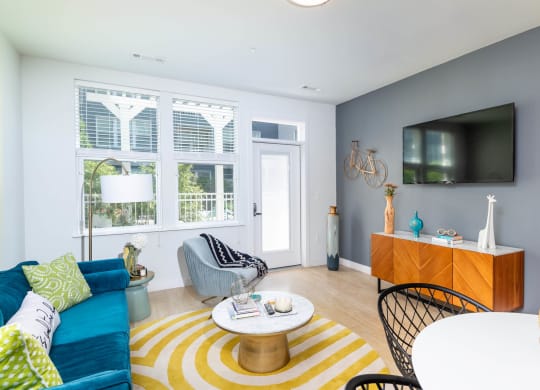 a living room with a blue couch and a yellow and white rug
