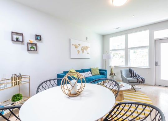 a dining room with a white table and chairs and a blue couch in the background