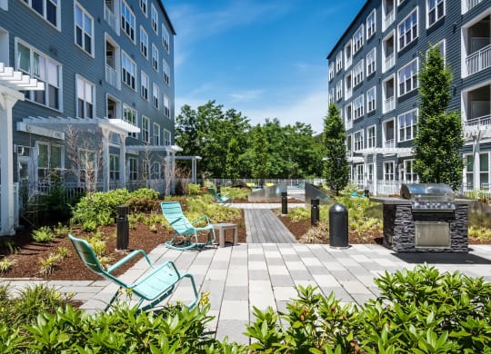 a patio with a fire pit and lounge chairs in front of a building