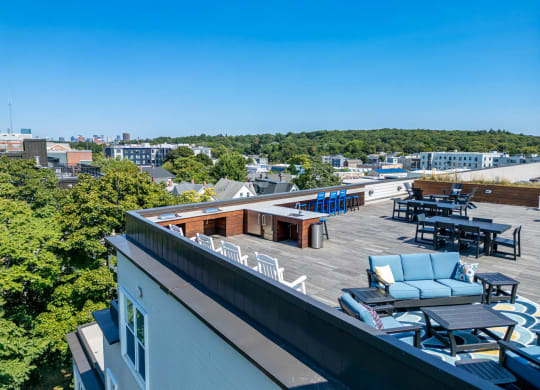 a rooftop deck with furniture and a view of the city