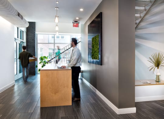 a man in a white shirt and black pants stands at the front desk of an office