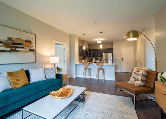 An inviting open-concept living area featuring a modern couch, coffee table, and decor, leading to a stylish kitchen.