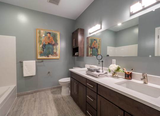 A bathroom with a toilet, sink, and a painting on the wall.