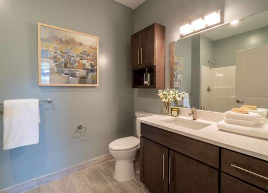 A bathroom with a toilet, sink, and a painting on the wall.