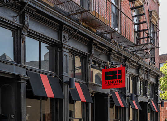 A black building with a red sign that says DENDEN cafe