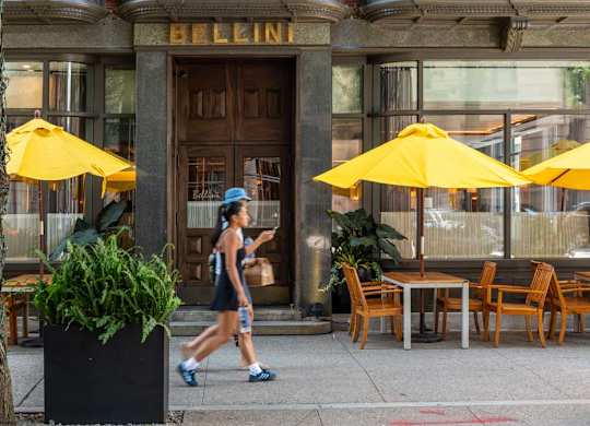 A woman is walking on the street in front of the Exchange Building.