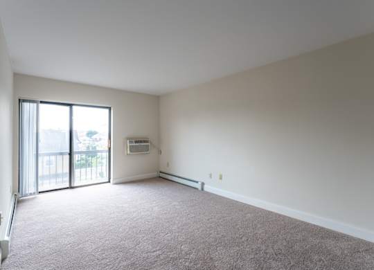 an empty living room with a sliding glass door to a balcony