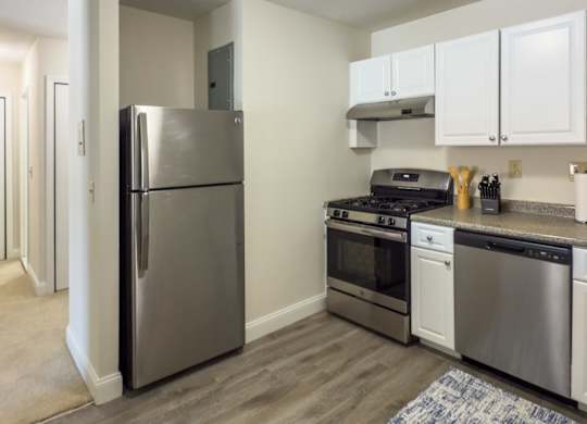 A kitchen with a refrigerator, oven, and stove.