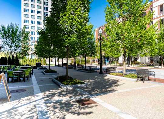 A park with benches and trees in front of a building.