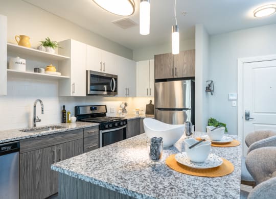 model kitchen with hanging island lights and undercabinet lighting, stainless appliances.