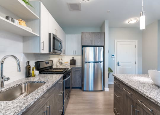 model apartment kitchen and granite counters, stainless steel appliances.
