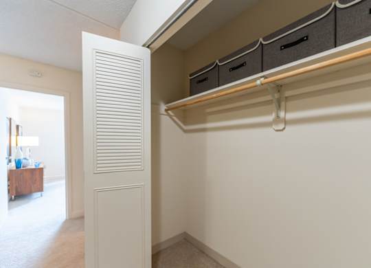 a walk in closet with white walls and a white door and a closet with shelves
