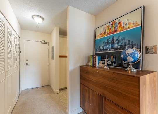A hallway with a wooden cabinet and a painting of a cityscape on the wall.