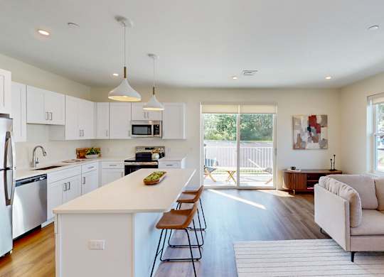 A kitchen with white cabinets and a white island with a bowl of fruit on it.