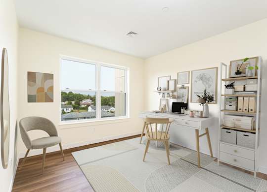 Versatile spare room staged as a home office with desk, shelving and wall art, illuminated by a broad window.