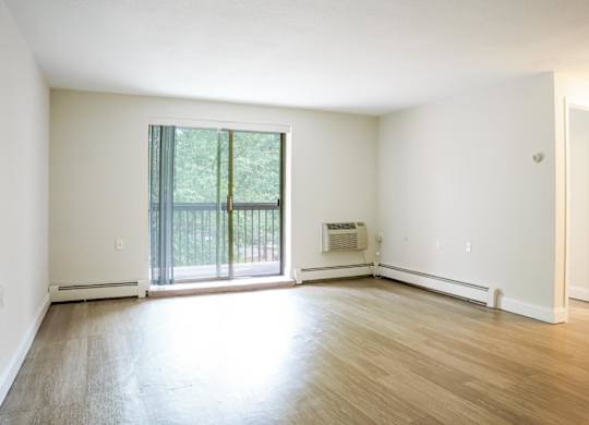 an empty living room with hardwood floors and a sliding glass door