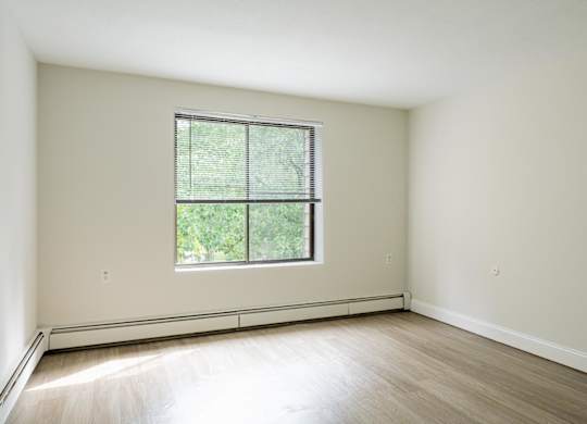 a bedroom with hardwood floors and a large window