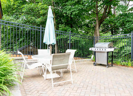 a patio with a table and chairs and a grill